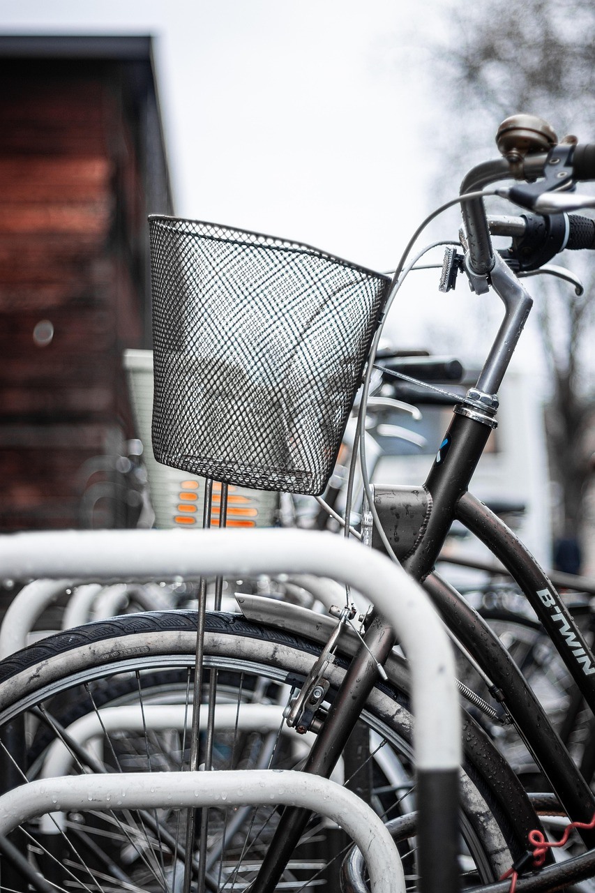 Several parked bicycles overlap in a close vertical view dominated by a wire basket, frames, and wheels.